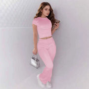 Woman wearing pink crop top and low rise flare leggings yoga set with white sneakers and silver handbag