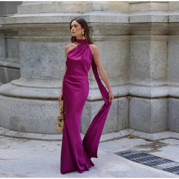 woman wearing halter backless off shoulder sleeveless purple ankle-length gown dress with diagonal collar in outdoor urban setting