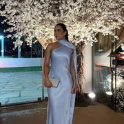 Woman wearing a sleeveless halter backless off shoulder solid ankle-length gown at night with floral tree background