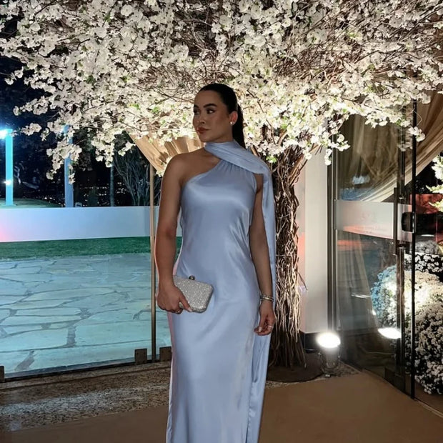 Woman wearing a sleeveless halter backless off shoulder solid ankle-length gown at night with floral tree background