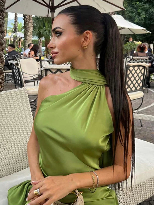 Woman wearing green satin halter dress with off-shoulder and sleeveless backless design sitting outdoors