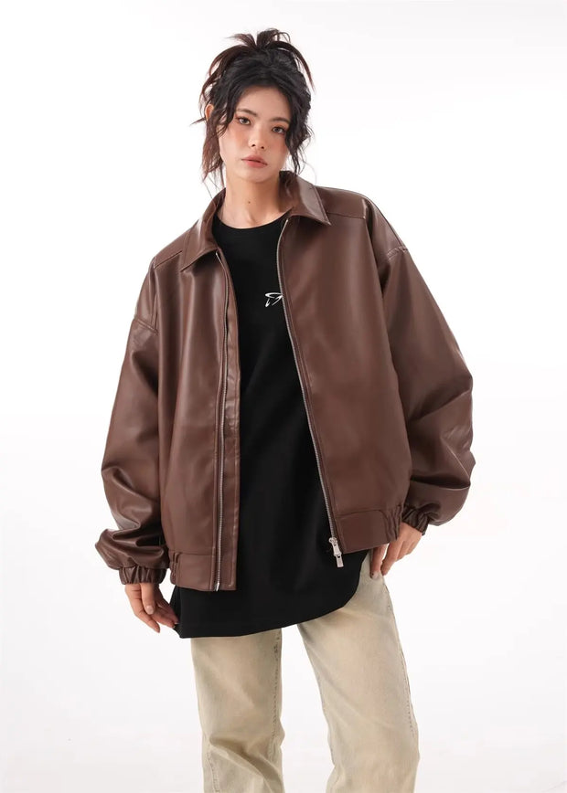 Brown faux PU leather rider jacket for women with long sleeves and a zipper closure, styled with a black top and beige pants.