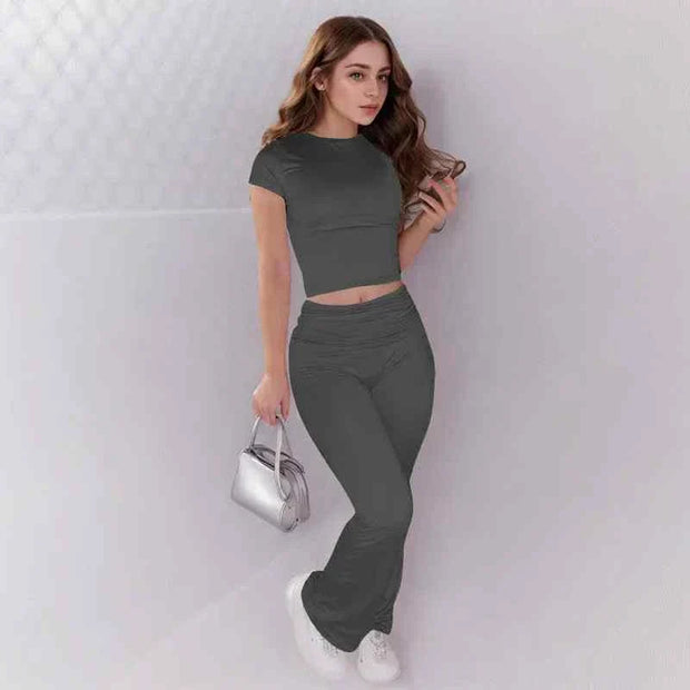 Woman wearing grey crop top and low rise flare leggings yoga pants set with white sneakers and silver handbag