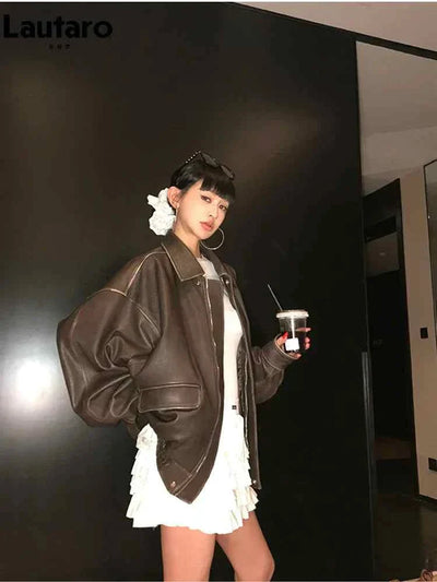 woman wearing soft faux leather brown jacket with zipper and turn-down collar holding drink indoors