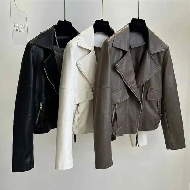 Three vintage style women's faux leather jackets in black, white, and brown with zipper closures and turn-down collars hanging on hangers.