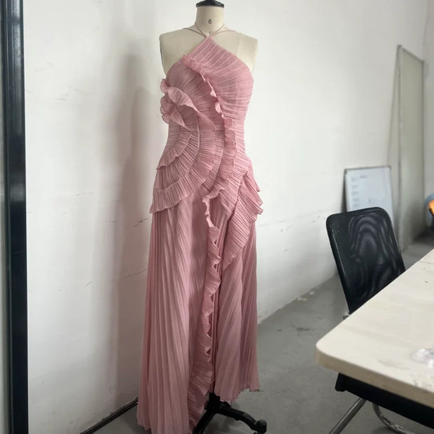 Slim fit backless pink pleated halter maxi dress with ruffle detailing on mannequin