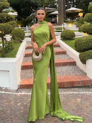 Woman wearing green halter backless off shoulder sleeveless ankle-length dress with slim fit and diagonal collar standing outdoors