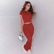 Woman wearing red crop top and low rise flare leggings yoga pants set with white sneakers and silver handbag