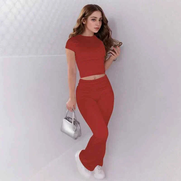 Woman wearing red crop top and low rise flare leggings yoga pants set with white sneakers and silver handbag