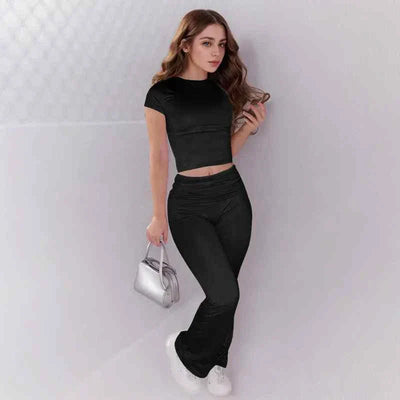 Woman wearing black crop top and low rise flare leggings yoga pants set with white sneakers and silver handbag
