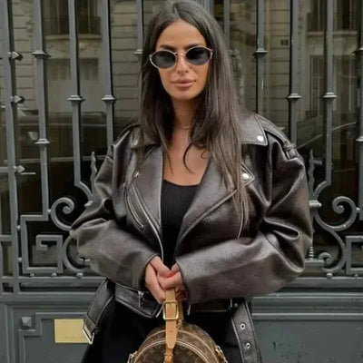 Women wearing retro short soft leather black biker jacket with belt and zipper outdoors