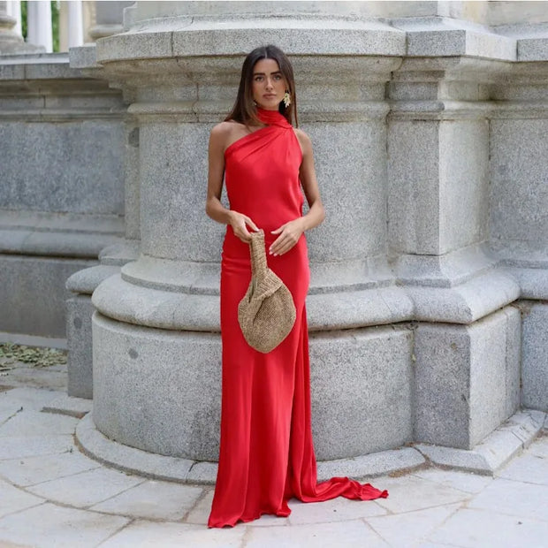 woman wearing red sexy backless off shoulder sleeveless long dress holding woven bag outdoors