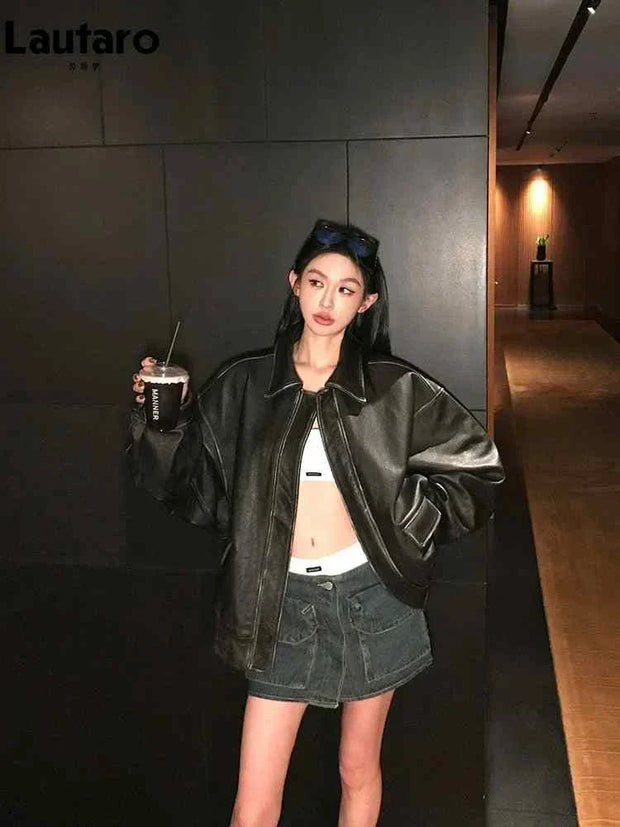 Woman wearing oversized soft faux leather jacket with zipper and turn-down collar holding a drink