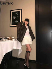 woman wearing soft faux leather oversized brown jacket with zipper and turn-down collar standing indoors